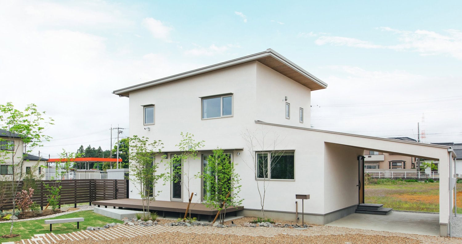 白い塗り壁の外観と庭、インナーガレージがつながる住まい