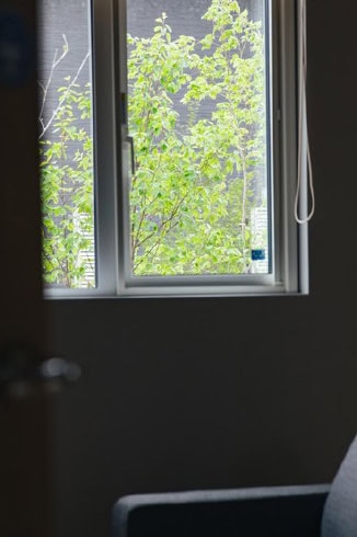 室内の窓から近くの植栽を望む落ち着いたリビング
